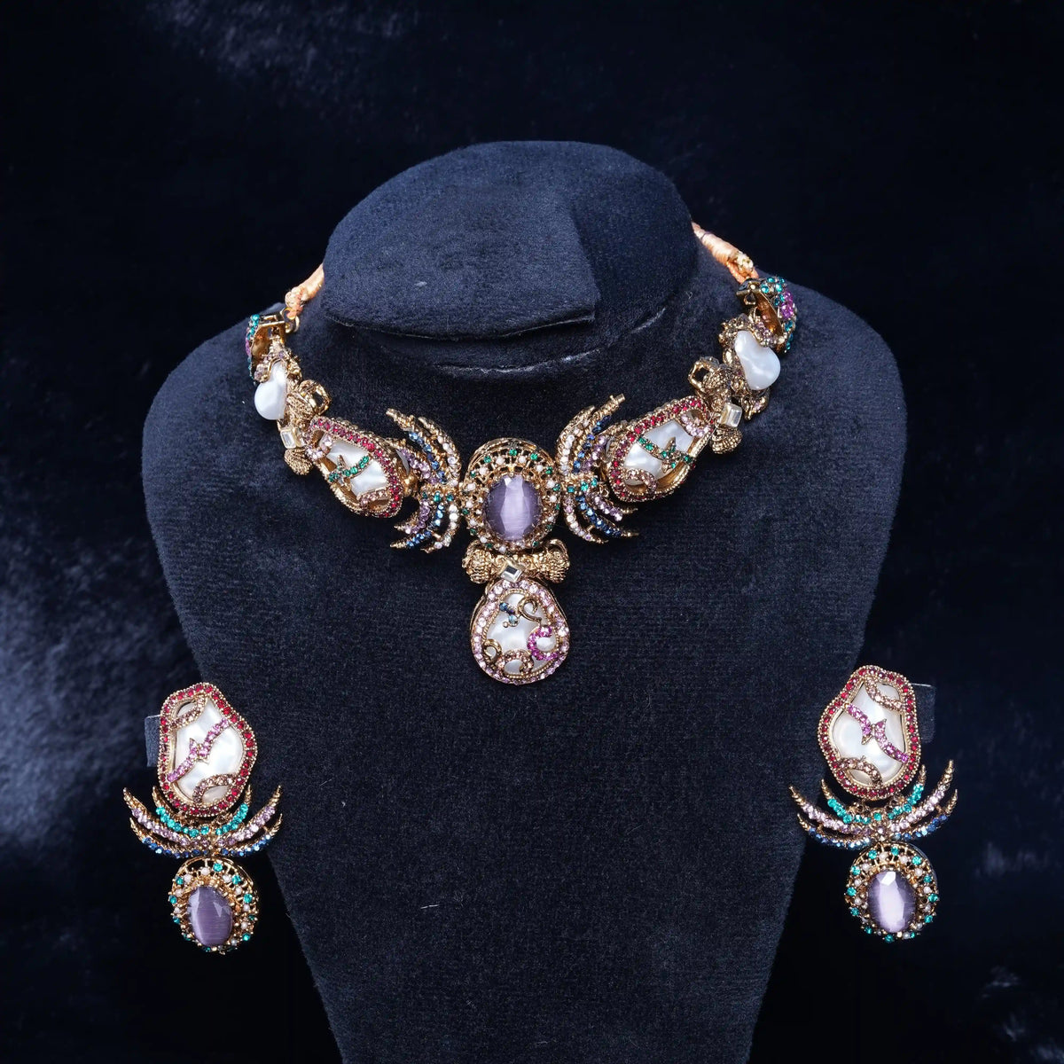 Jewelry set with necklace and earrings on a black stand against a dark background