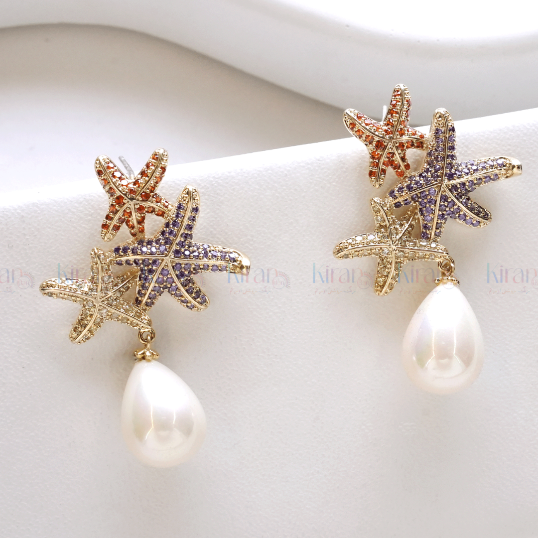 A pair of earrings featuring starfish designs with multicolored crystals and a teardrop pearl dangling at the bottom.