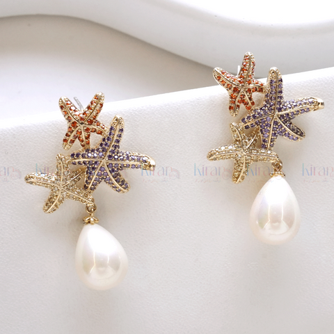 A pair of earrings featuring starfish designs with multicolored crystals and a teardrop pearl dangling at the bottom.