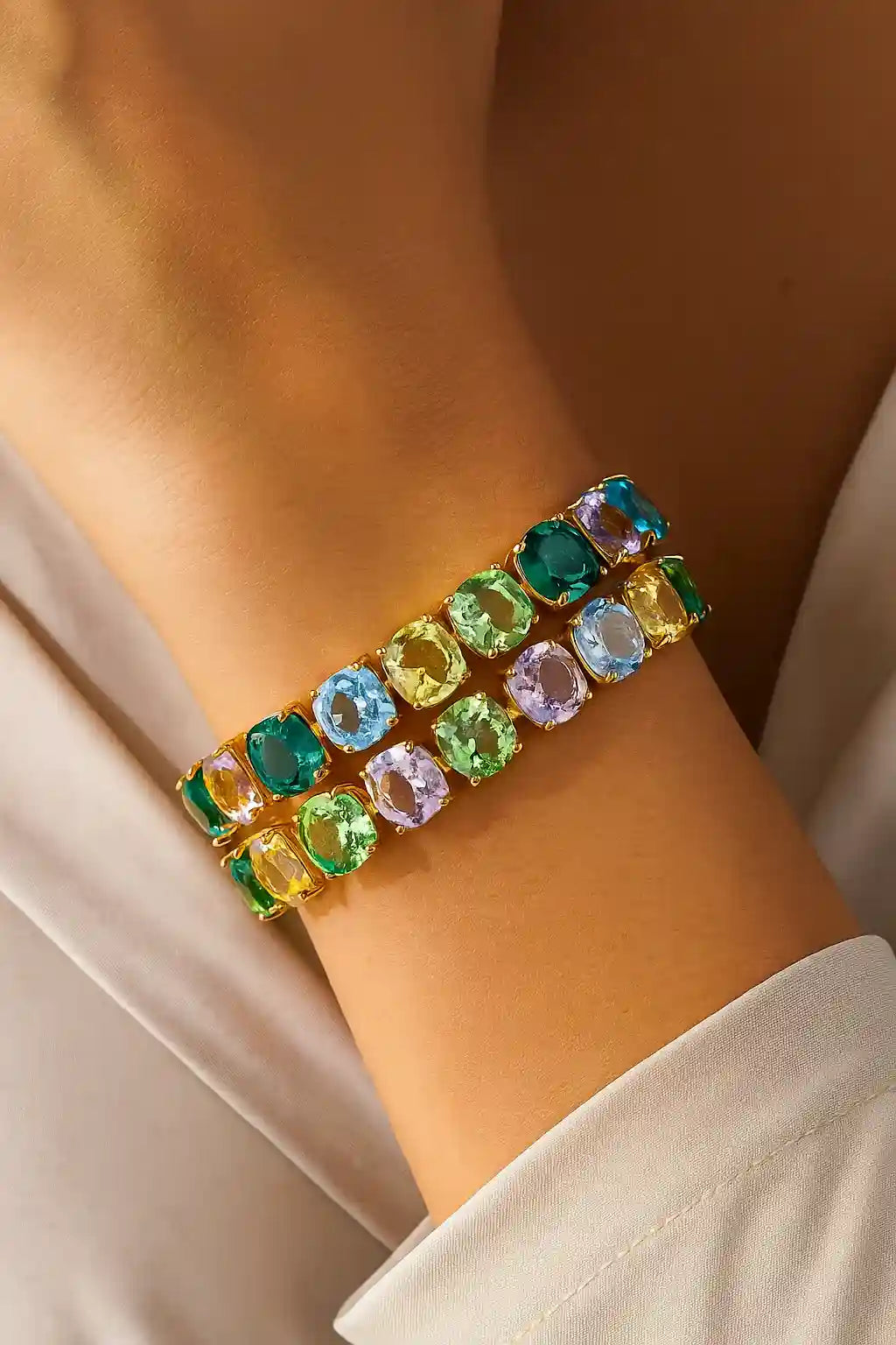 Multicolored gemstone bracelet on a wrist with a neutral background