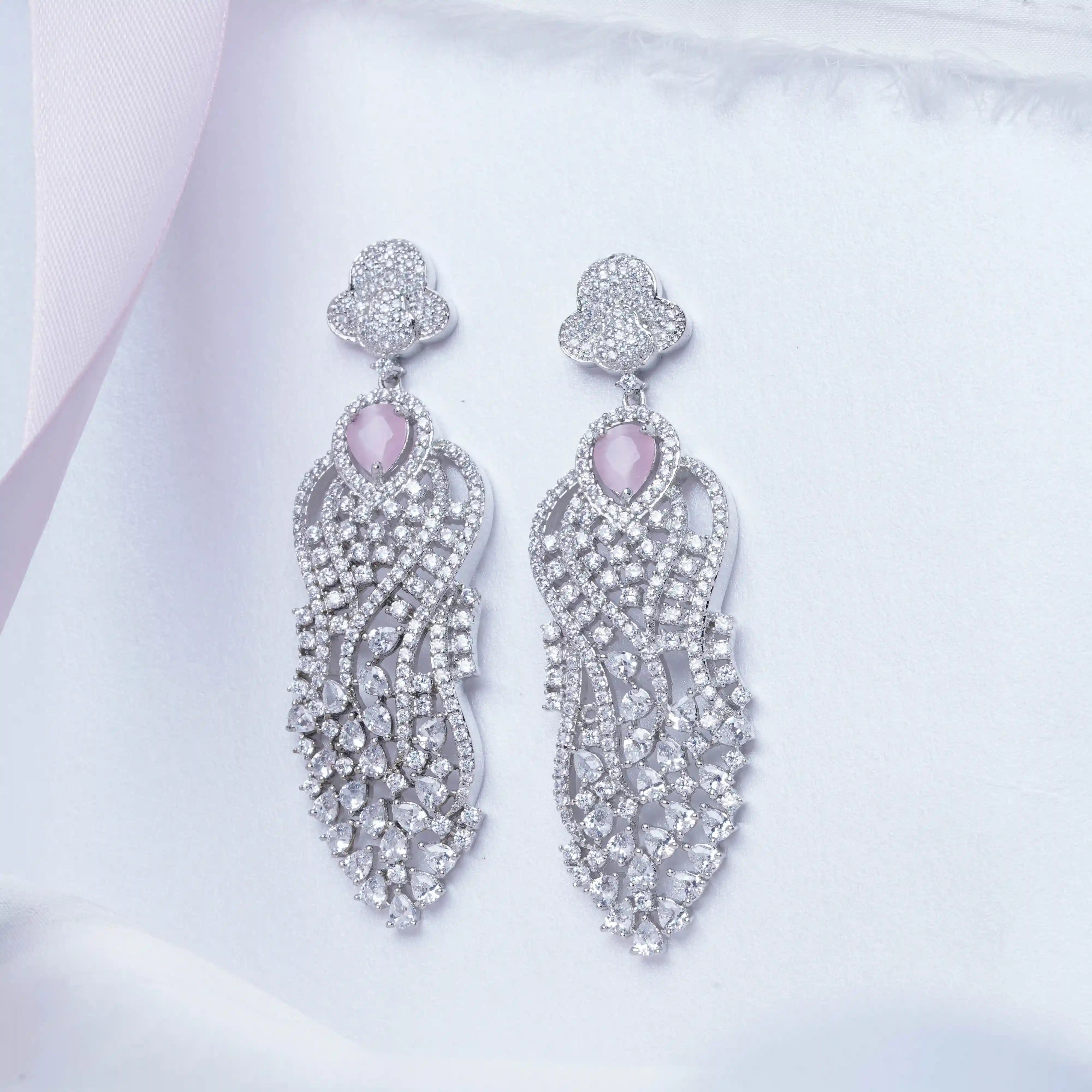 Pair of silver earrings with pink gemstones on a light background