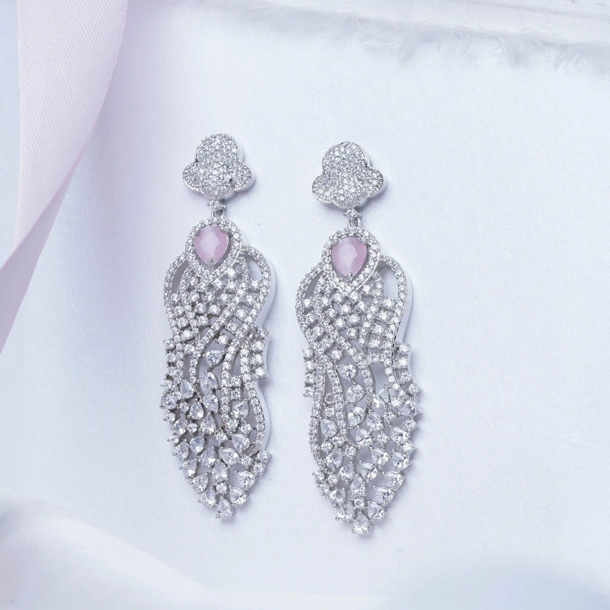 Pair of silver earrings with pink gemstones on a light background