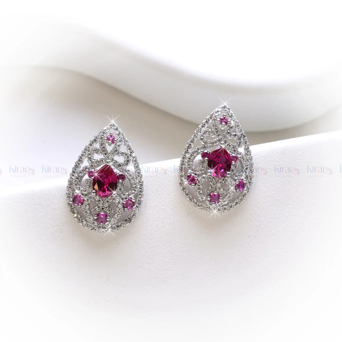 Teardrop-shaped earrings with pink gemstones on a white background