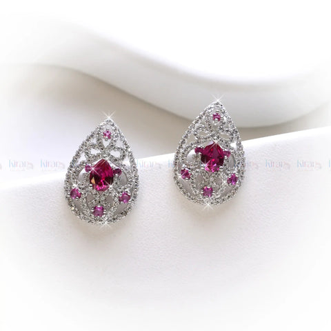 Teardrop-shaped earrings with pink gemstones on a white background