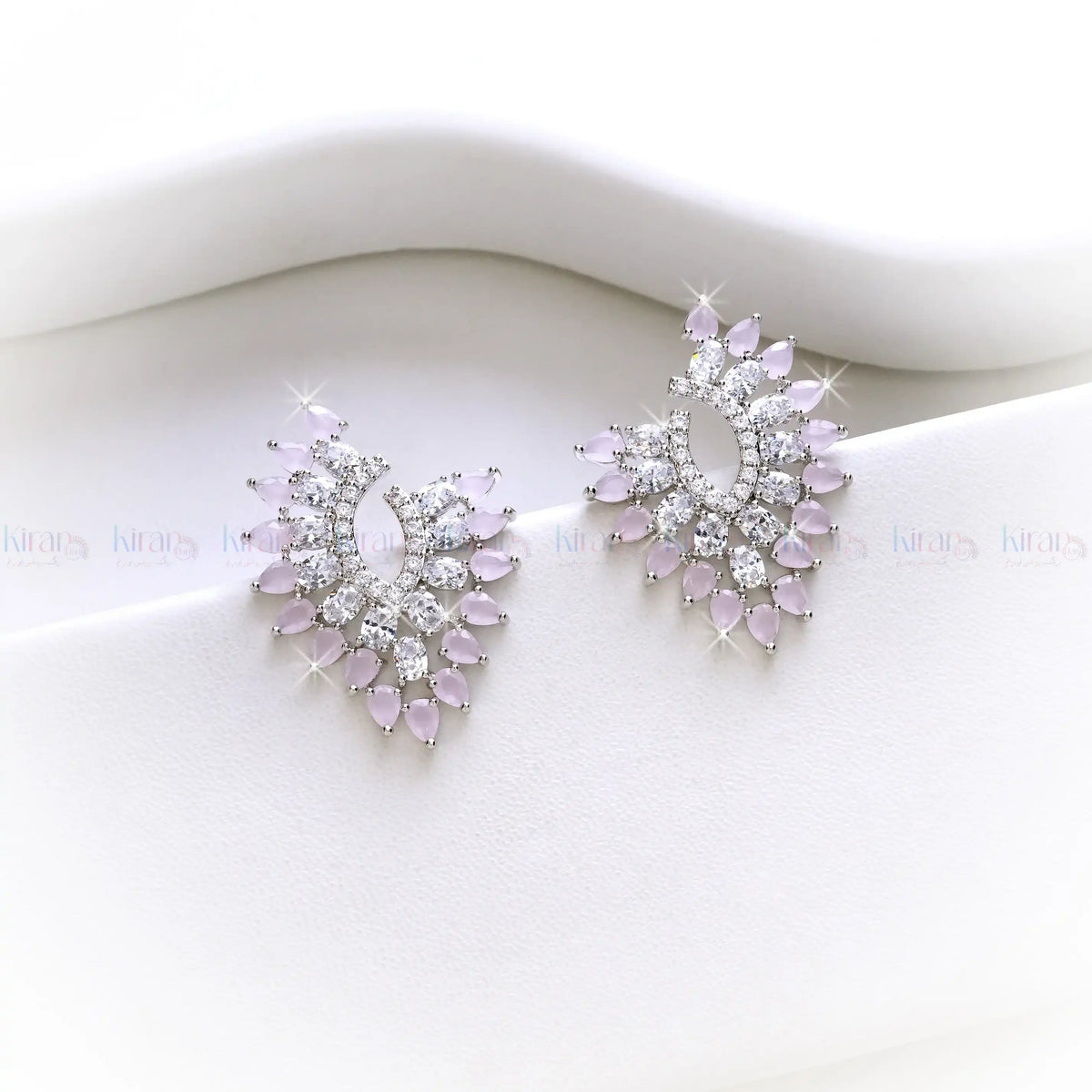 Pair of earrings with pink gemstones and clear stones on a white background