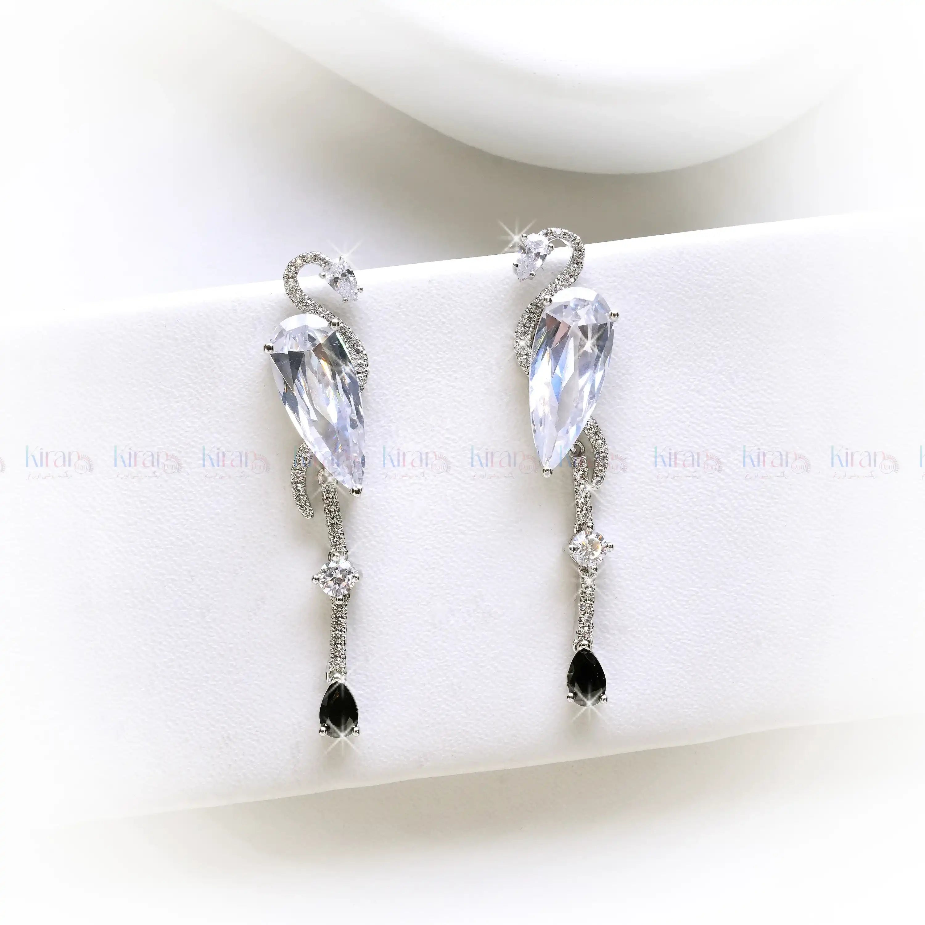 Pair of earrings with clear and black gemstones on a white surface