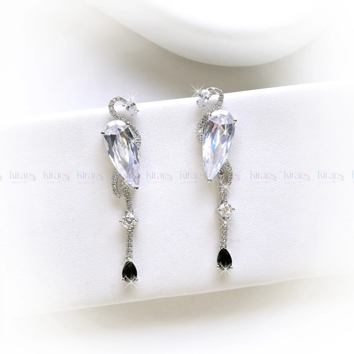 Pair of earrings with clear and black gemstones on a white surface