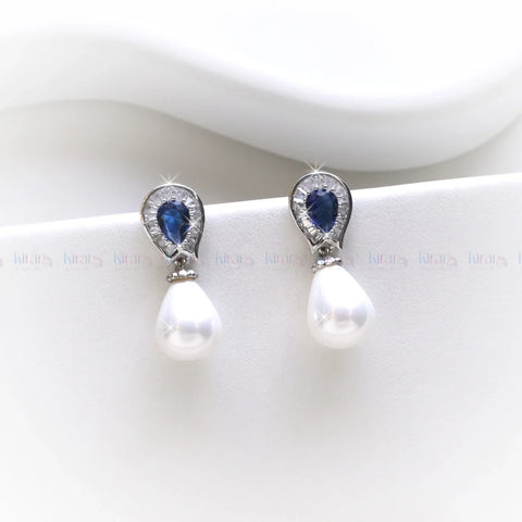 Pair of earrings with pearls and blue gemstones on a white background