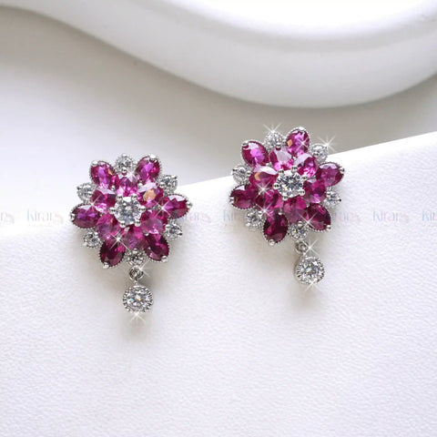 Pair of pink flower-shaped earrings with clear stones on a white background
