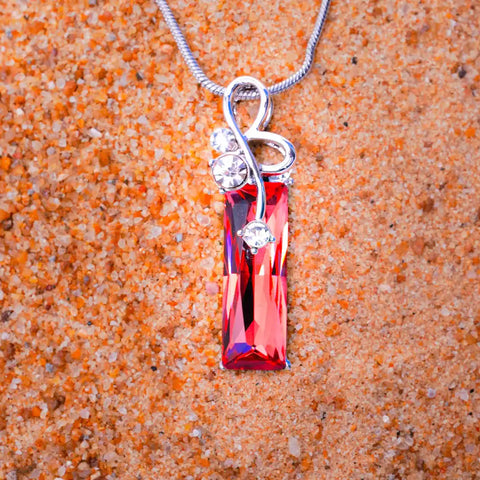 Necklace with a red pendant on an orange sand background