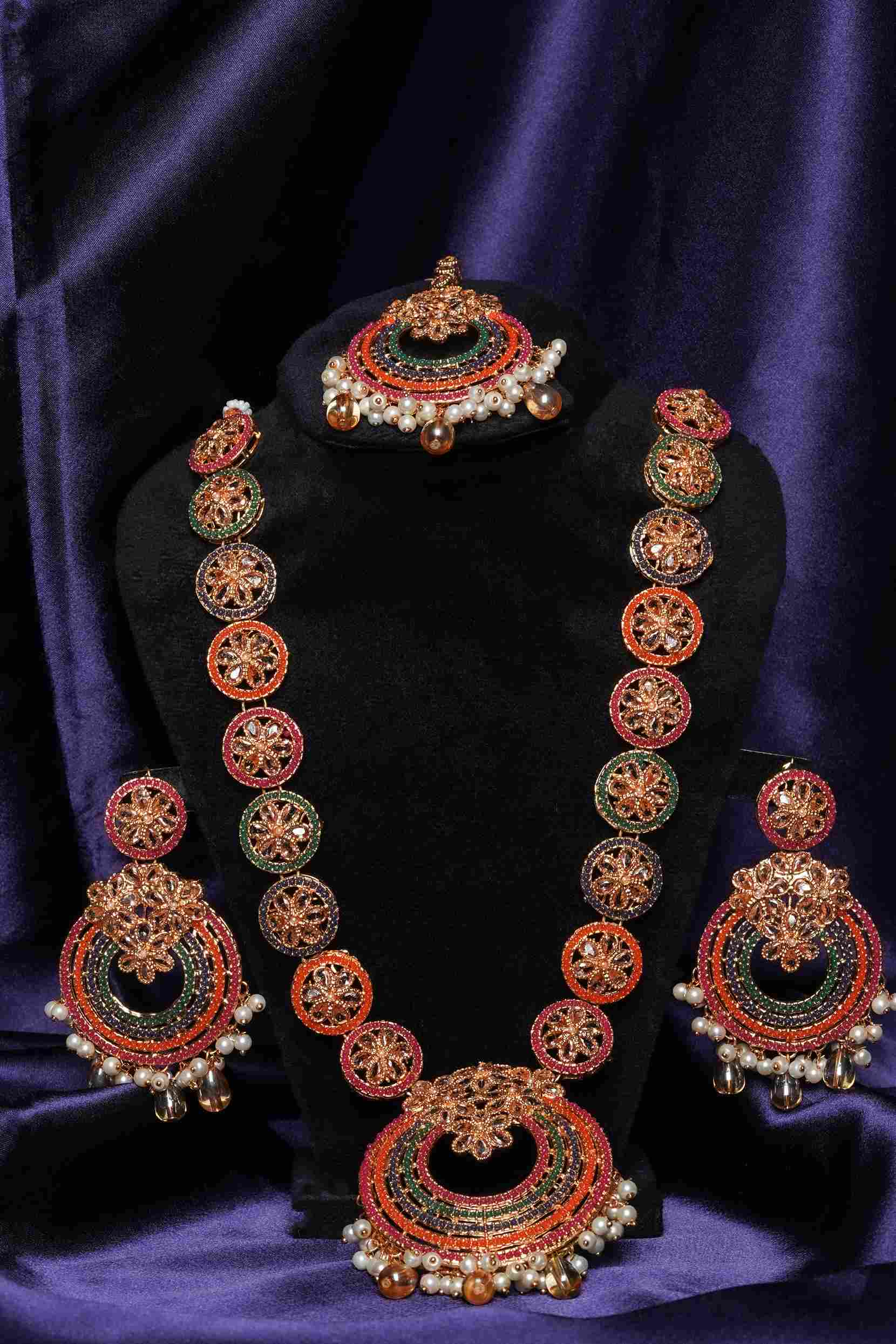 Ornate necklace and earrings set on a dark purple background