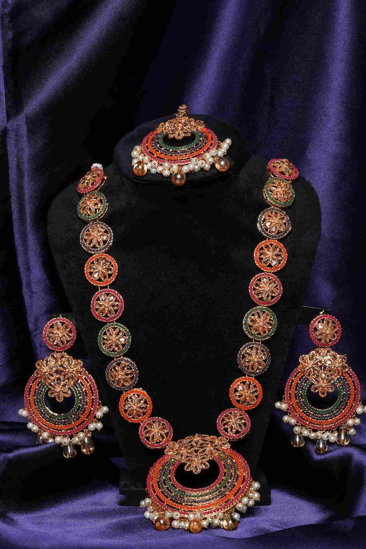 Ornate necklace and earrings set on a dark purple background