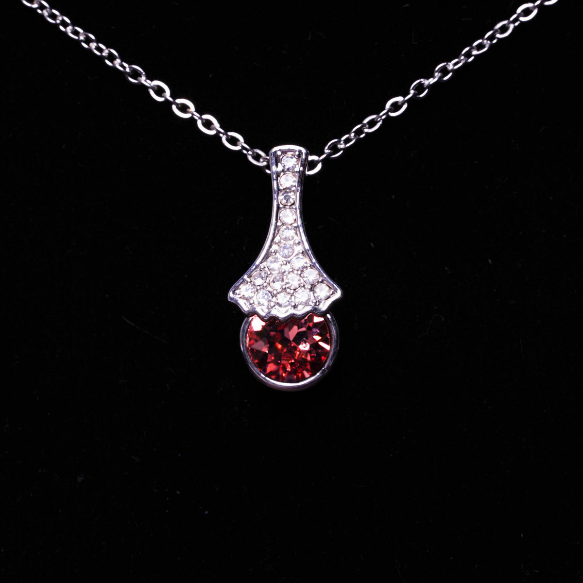 Necklace with a pendant featuring a red gemstone on a black background