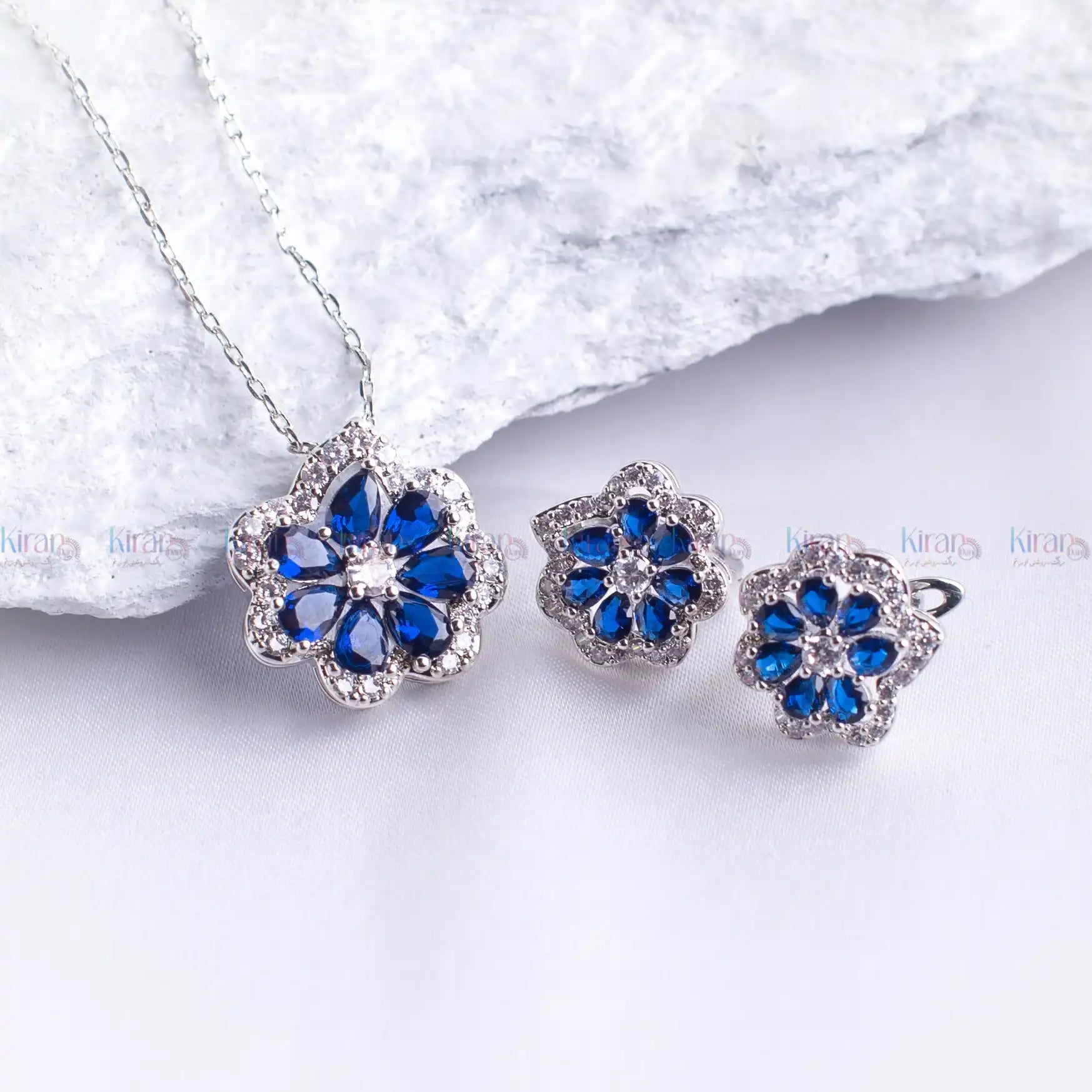 Jewelry set with blue flower-shaped stones on a white background