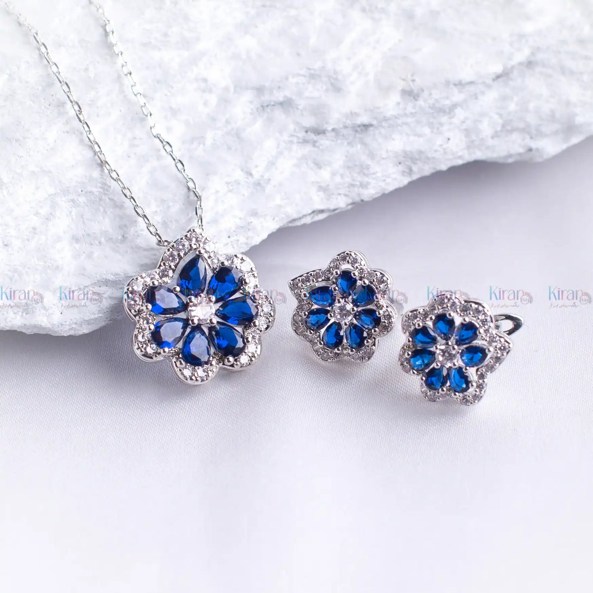Jewelry set with blue flower-shaped stones on a white background