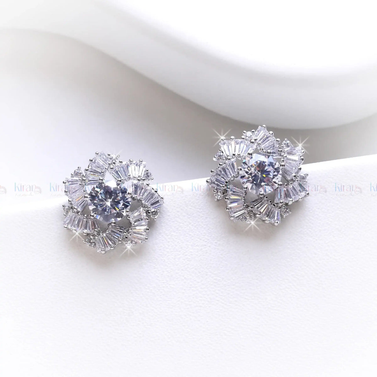 Pair of silver earrings with clear gemstones on a white background
