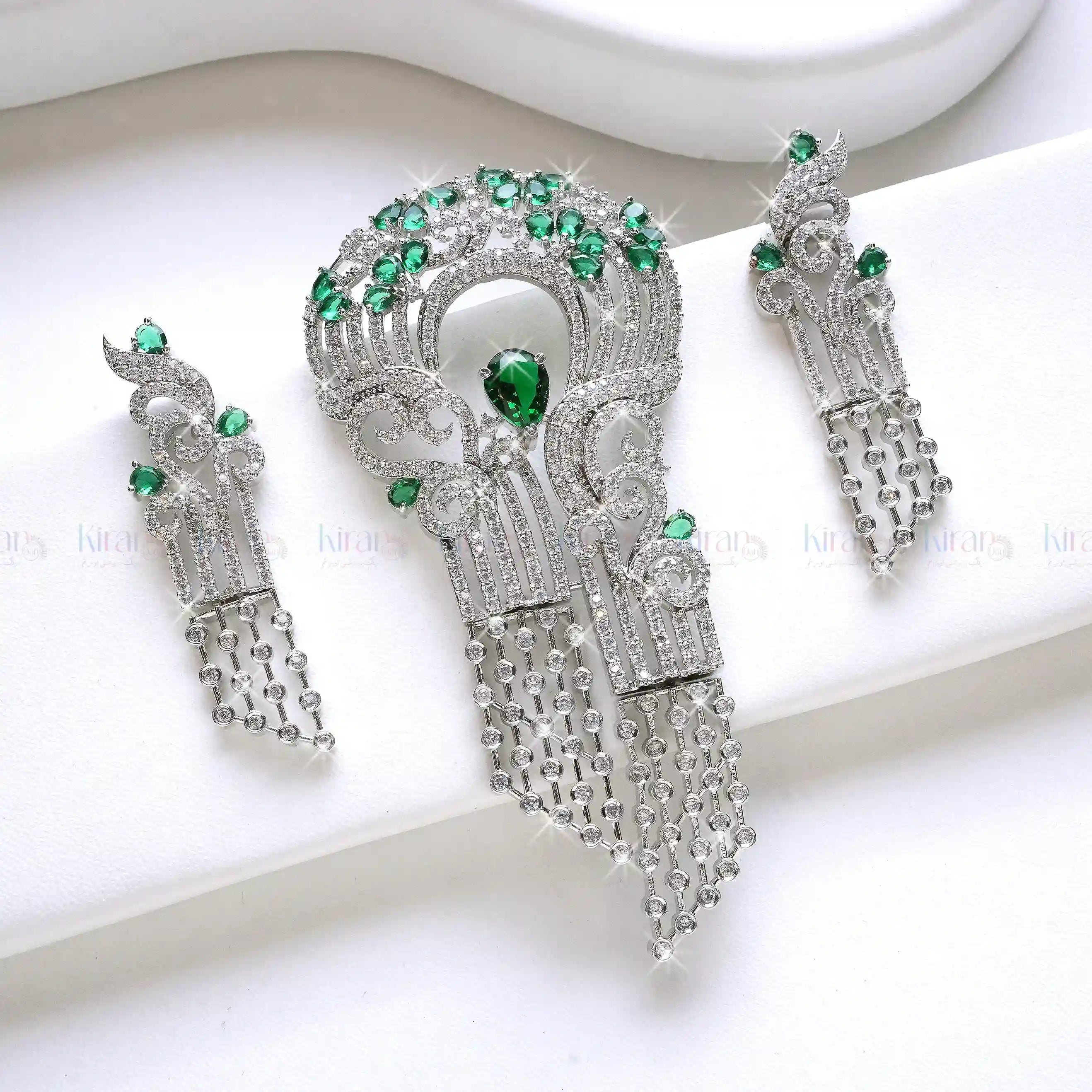 Ornate silver earrings with green gemstones on a white background