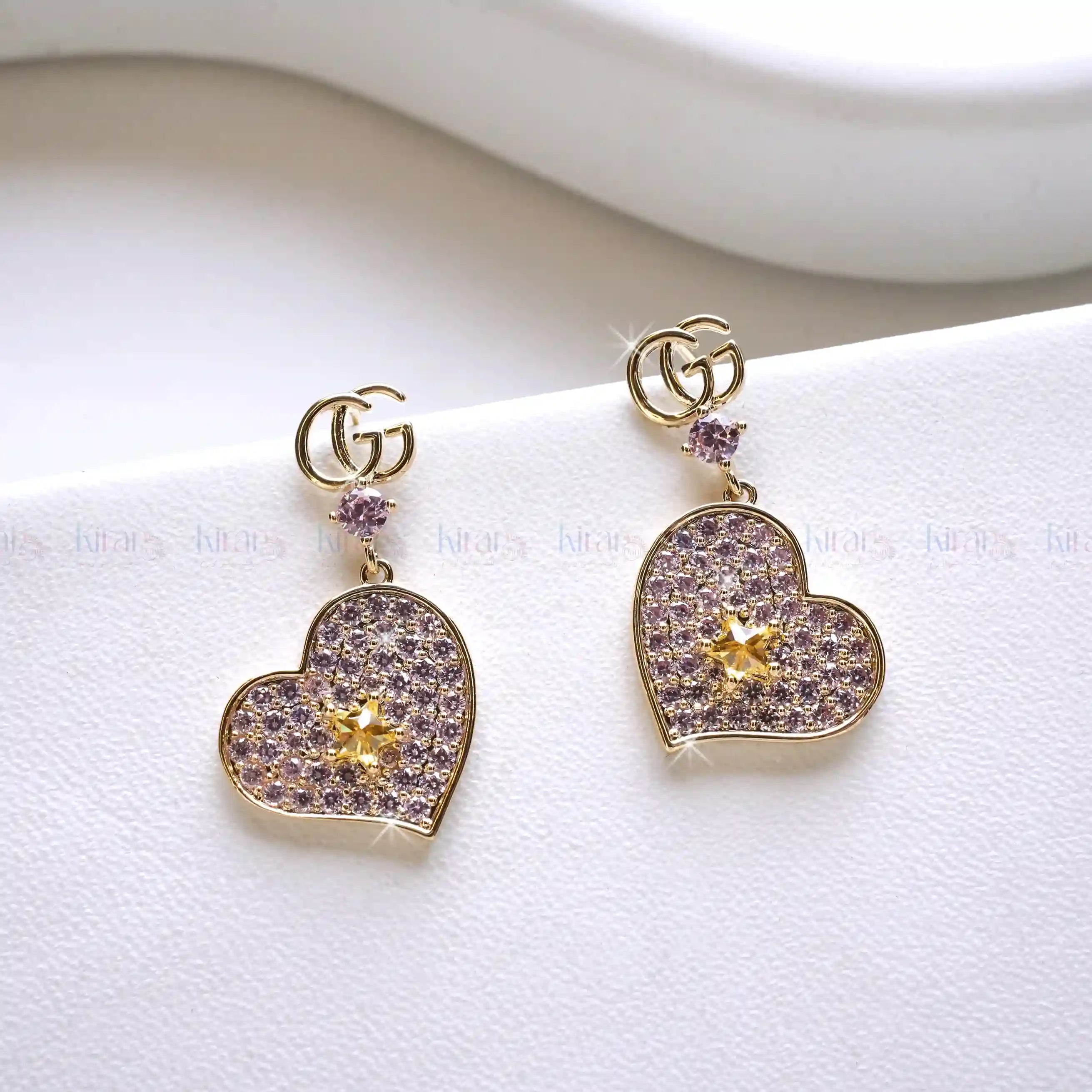 Heart-shaped earrings with gold and purple details on a white background
