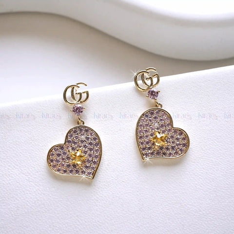 Heart-shaped earrings with gold and purple details on a white background