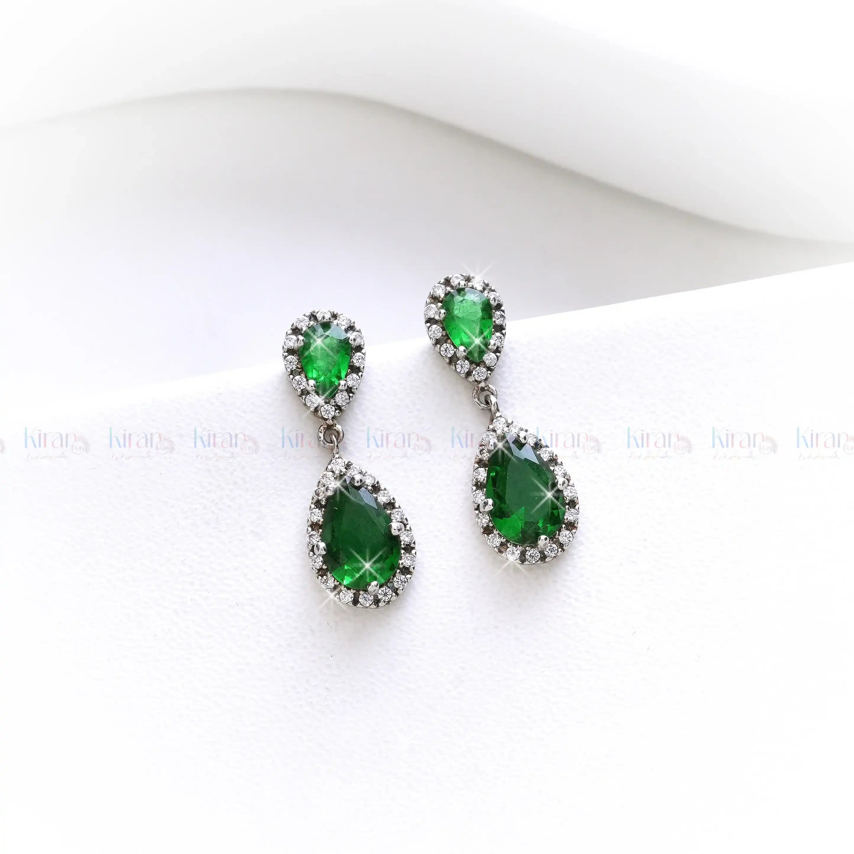 Pair of green teardrop earrings on a white background