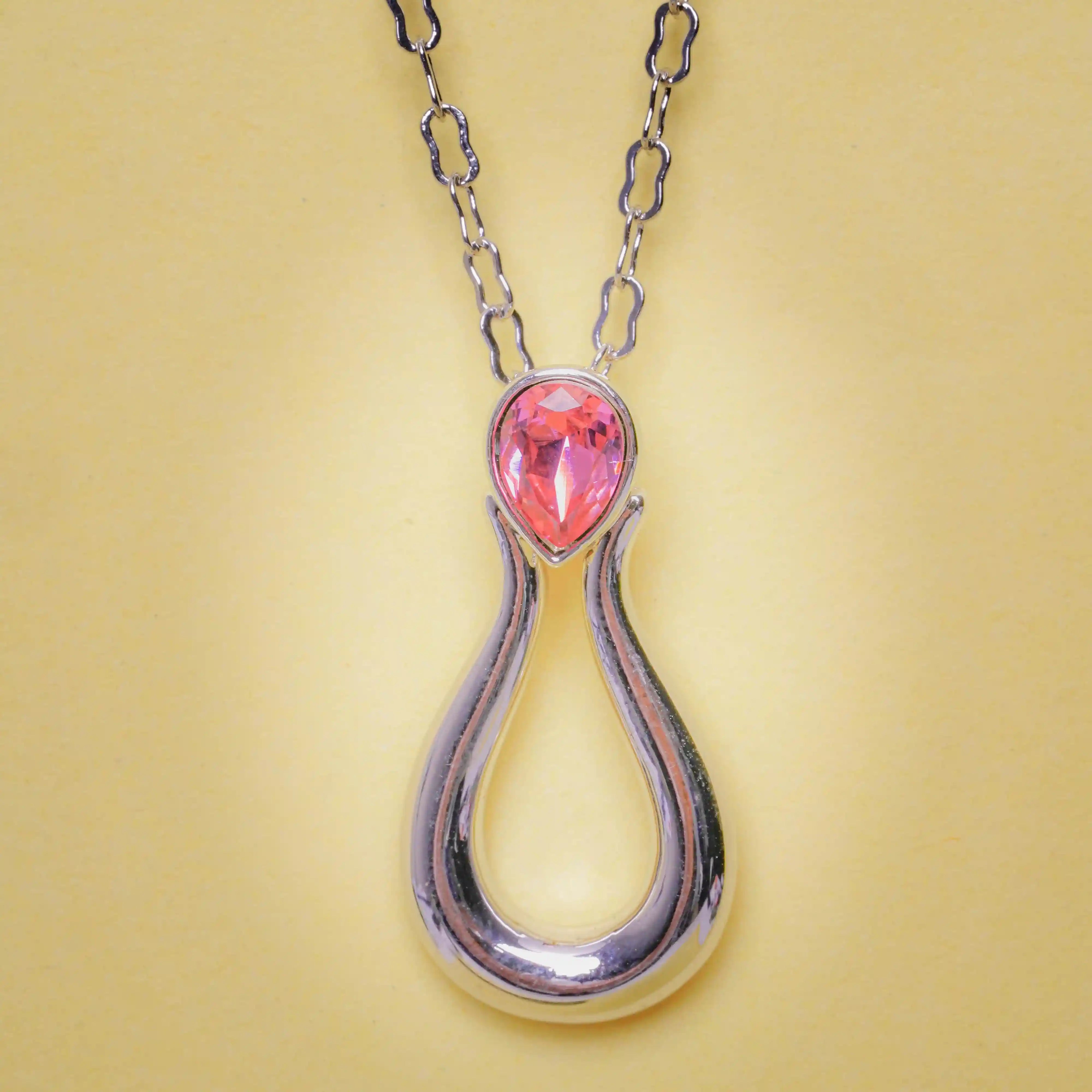 Necklace with a pink teardrop pendant on a yellow background