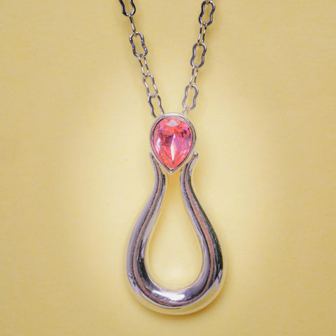Necklace with a pink teardrop pendant on a yellow background