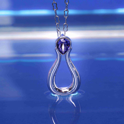 Silver necklace with a purple gemstone pendant on a blue reflective surface