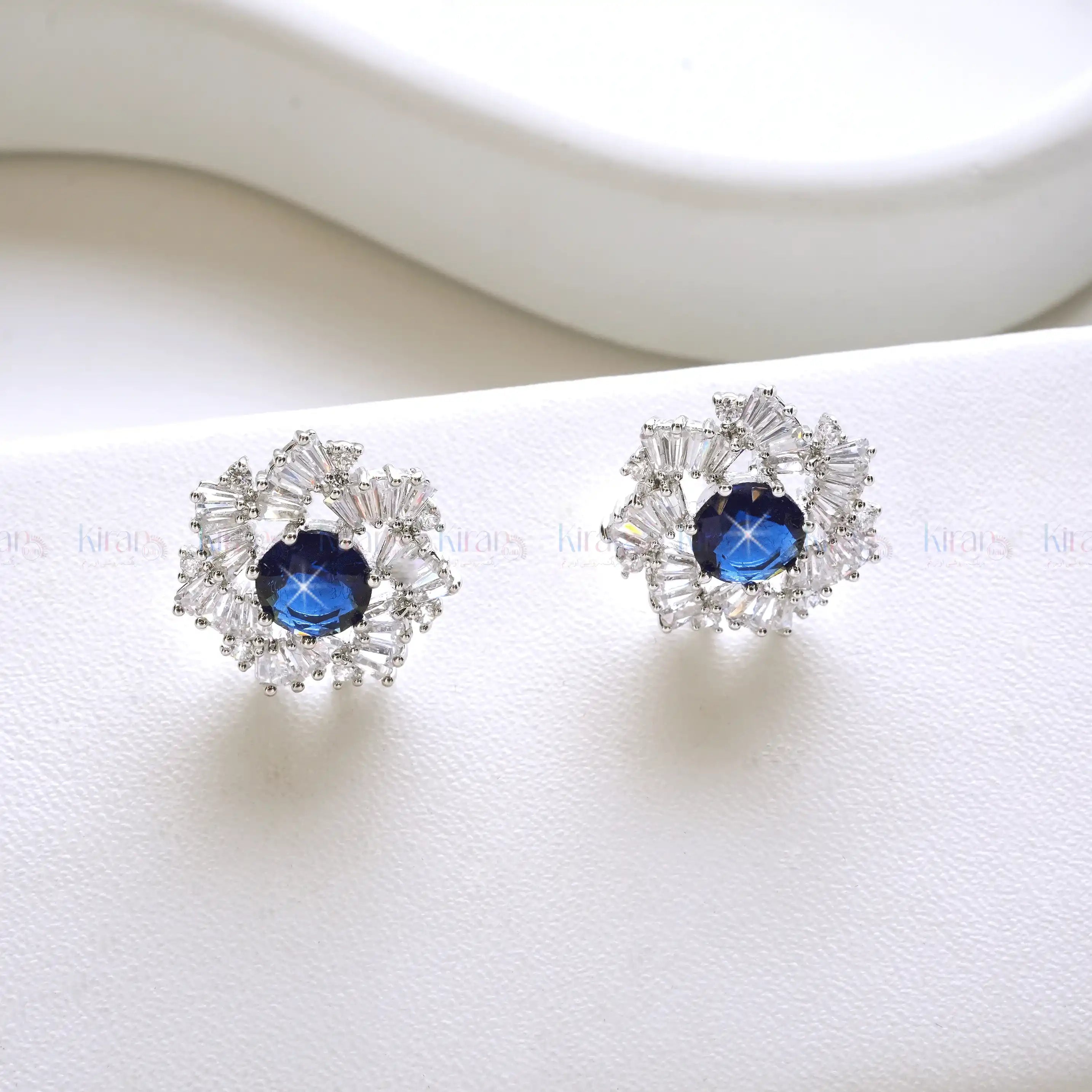 Pair of silver earrings with blue gemstones on a white background