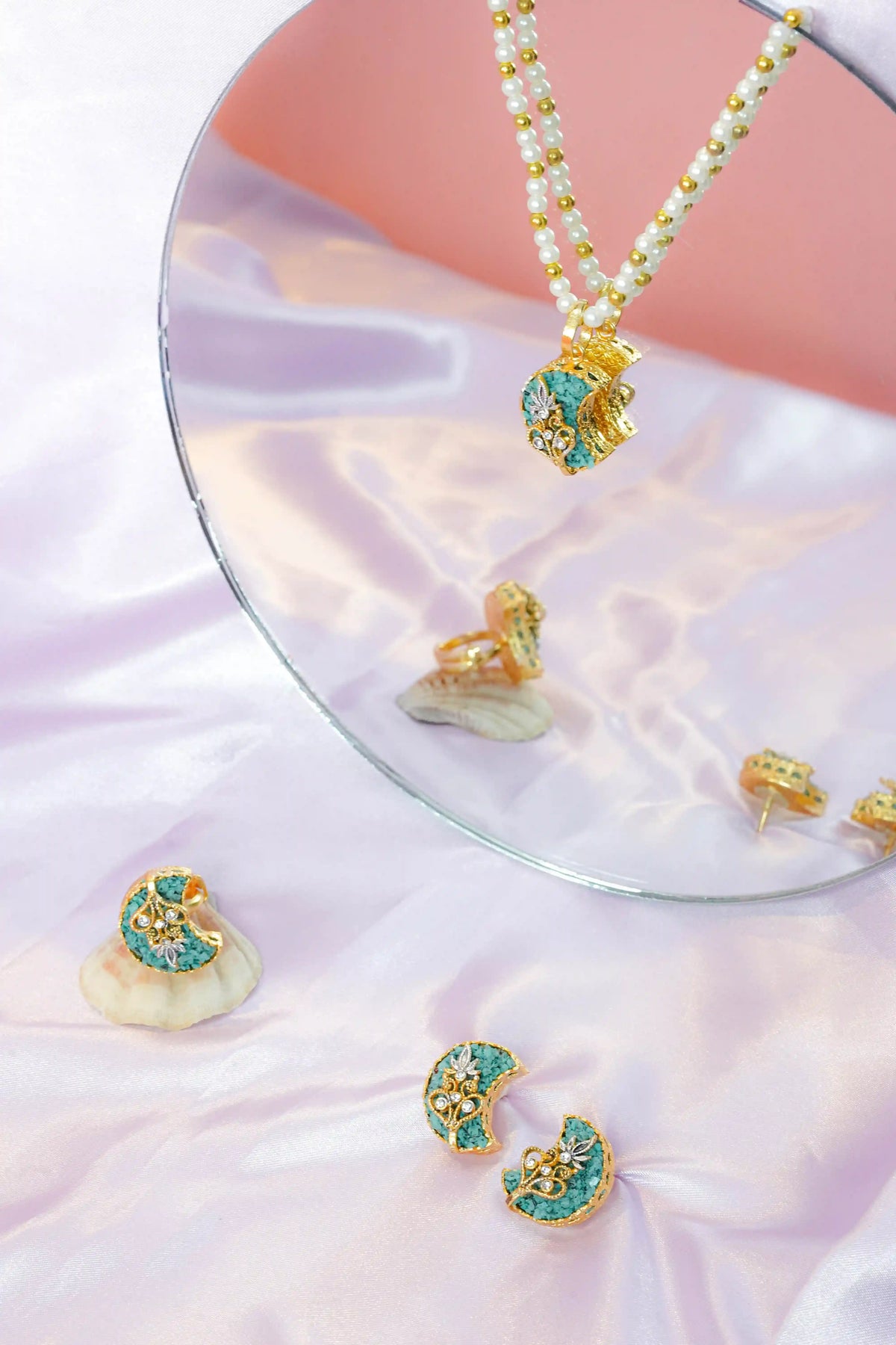 Jewelry set with earrings and a necklace on a pink fabric background