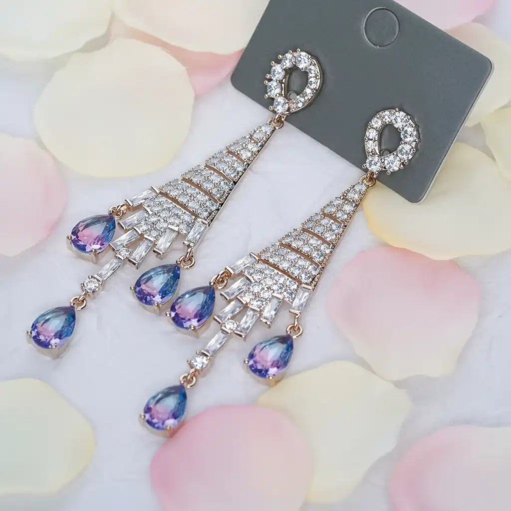 Elegant earrings with gemstones on a gray card against a soft floral background