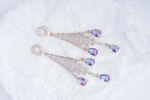 Pair of diamond earrings with purple gemstones on a white background