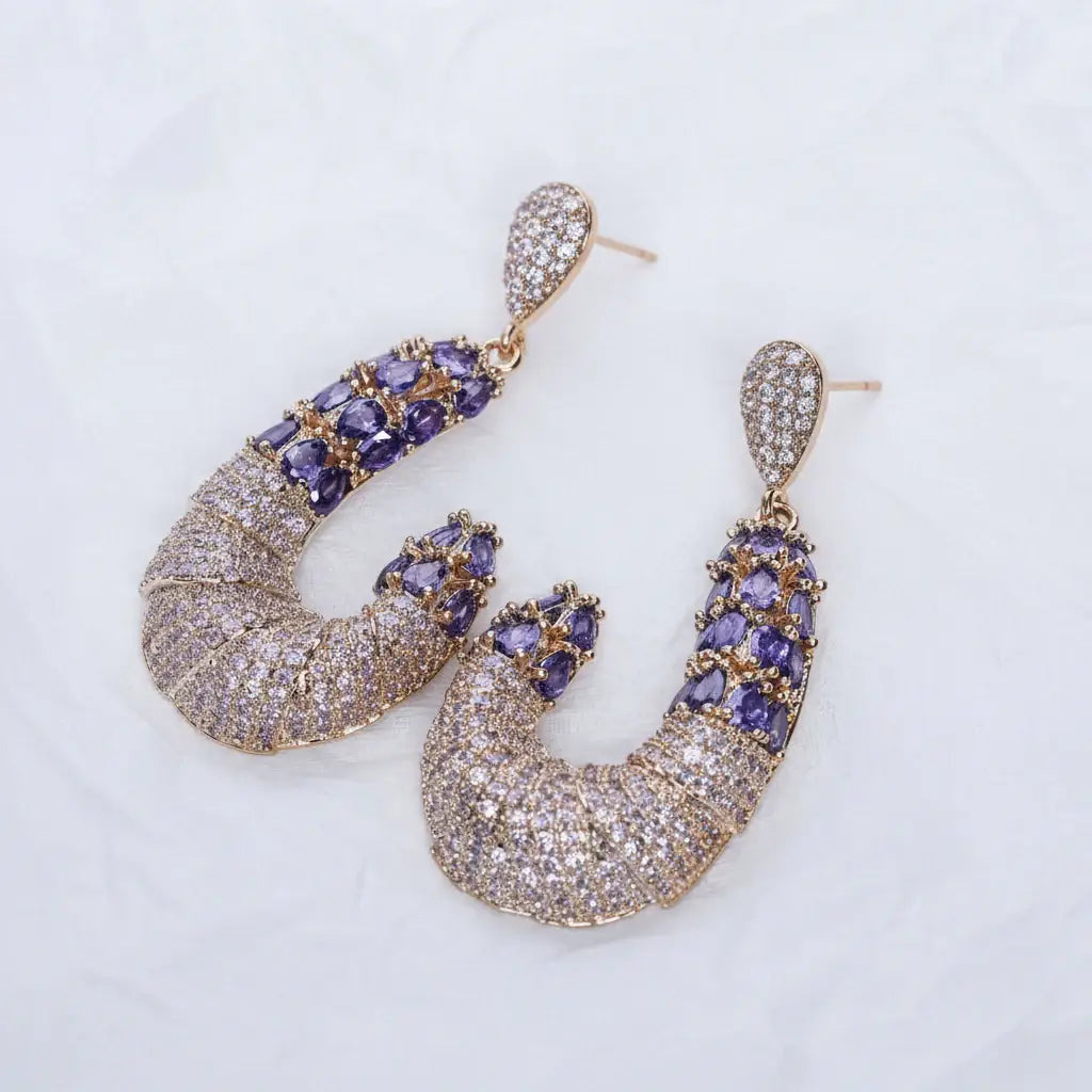 Pair of gold and purple earrings on a light gray background