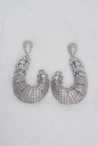 Pair of silver earrings with clear stones on a white background