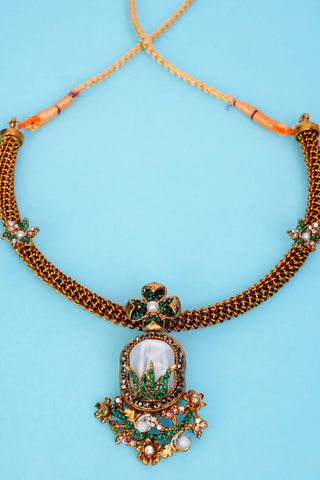 Ornate necklace with a detailed pendant on a light blue background