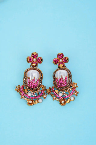 Pair of ornate earrings with pink and gold details on a blue background