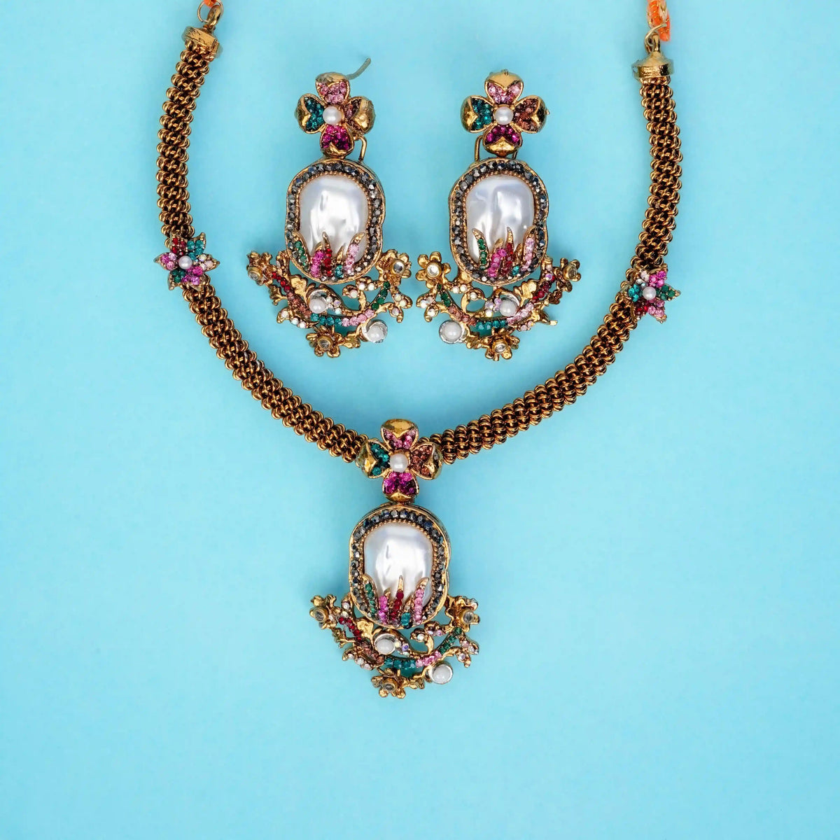 Ornate necklace and earrings set on a light blue background