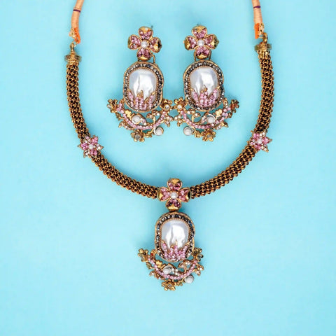 Ornate necklace and earrings set on a light blue background