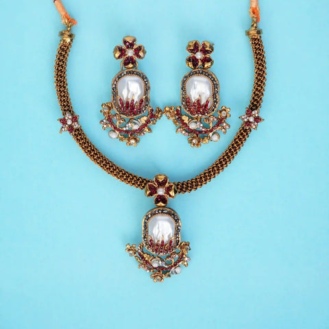 Ornate necklace and earrings set on a light blue background