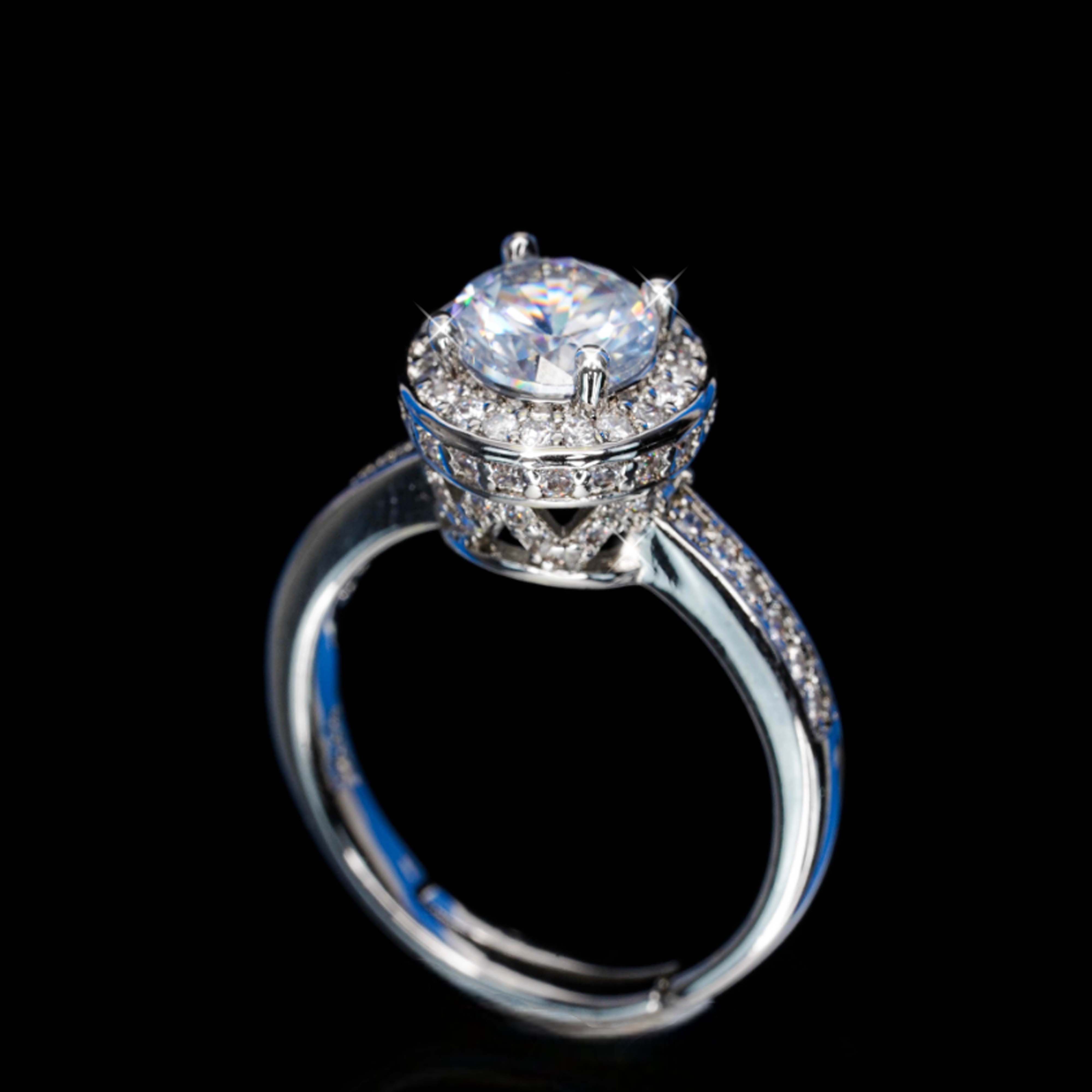 Silver ring with a large central gemstone and smaller stones on a black background