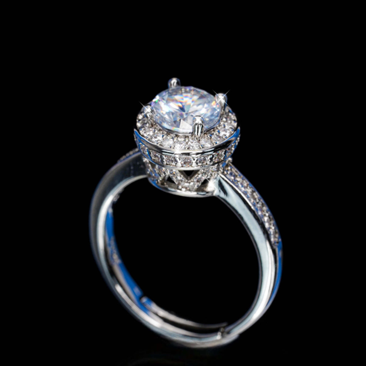 Silver ring with a large central gemstone and smaller stones on a black background