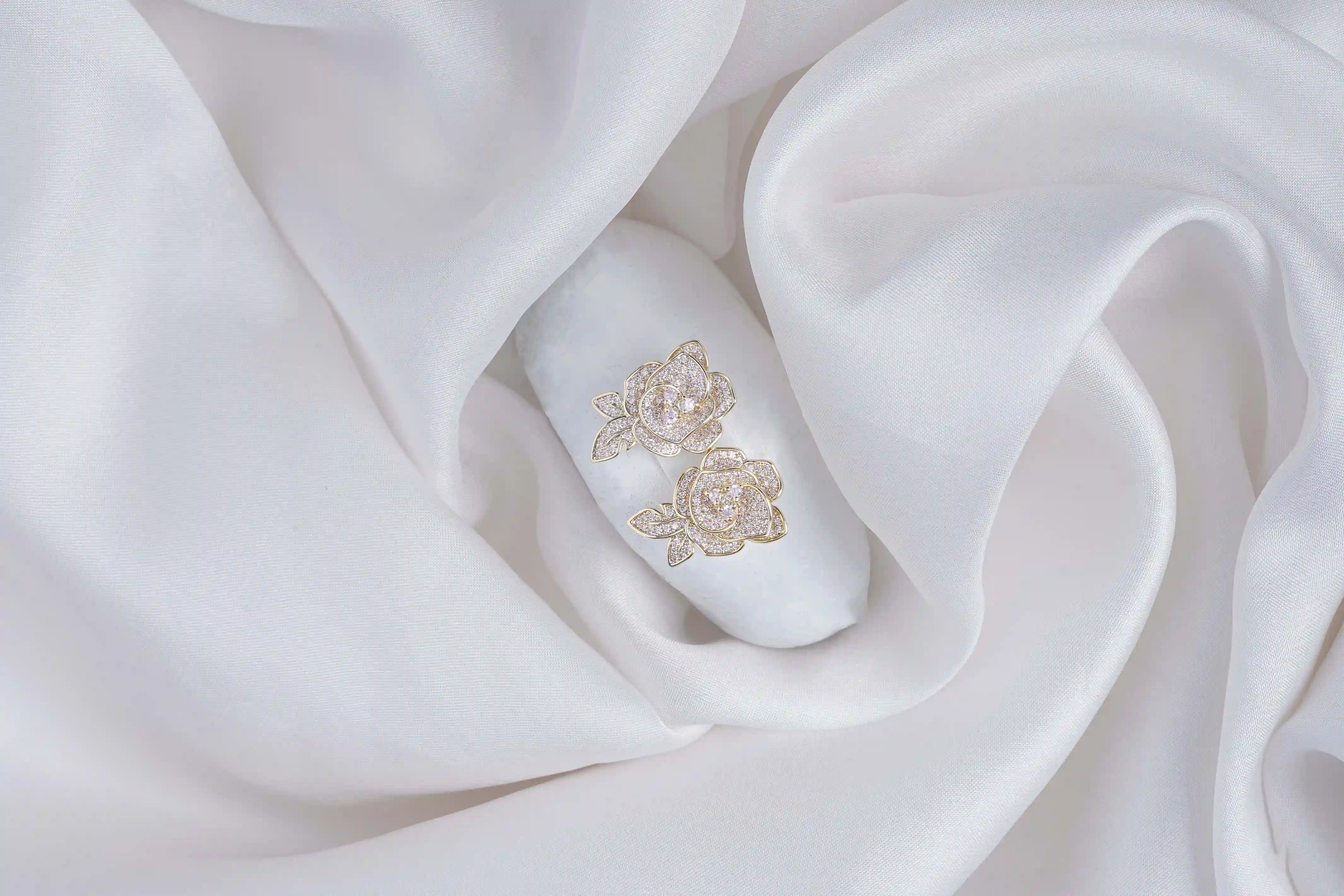 White nail with gold floral design on a white fabric background