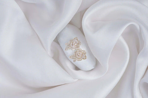 White nail with gold floral design on a white fabric background
