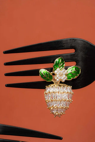 Decorative hairpin with green leaves on a black fork against an orange background