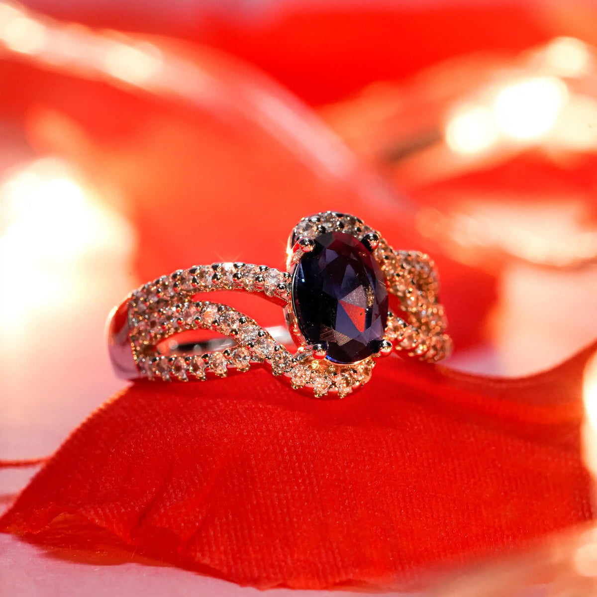 Gold ring with a dark gemstone on a red fabric background