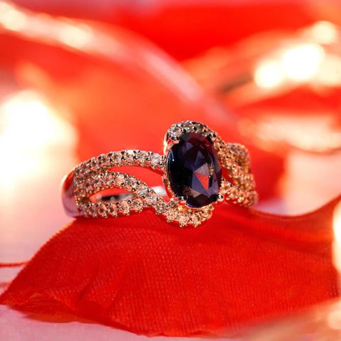Gold ring with a dark gemstone on a red fabric background
