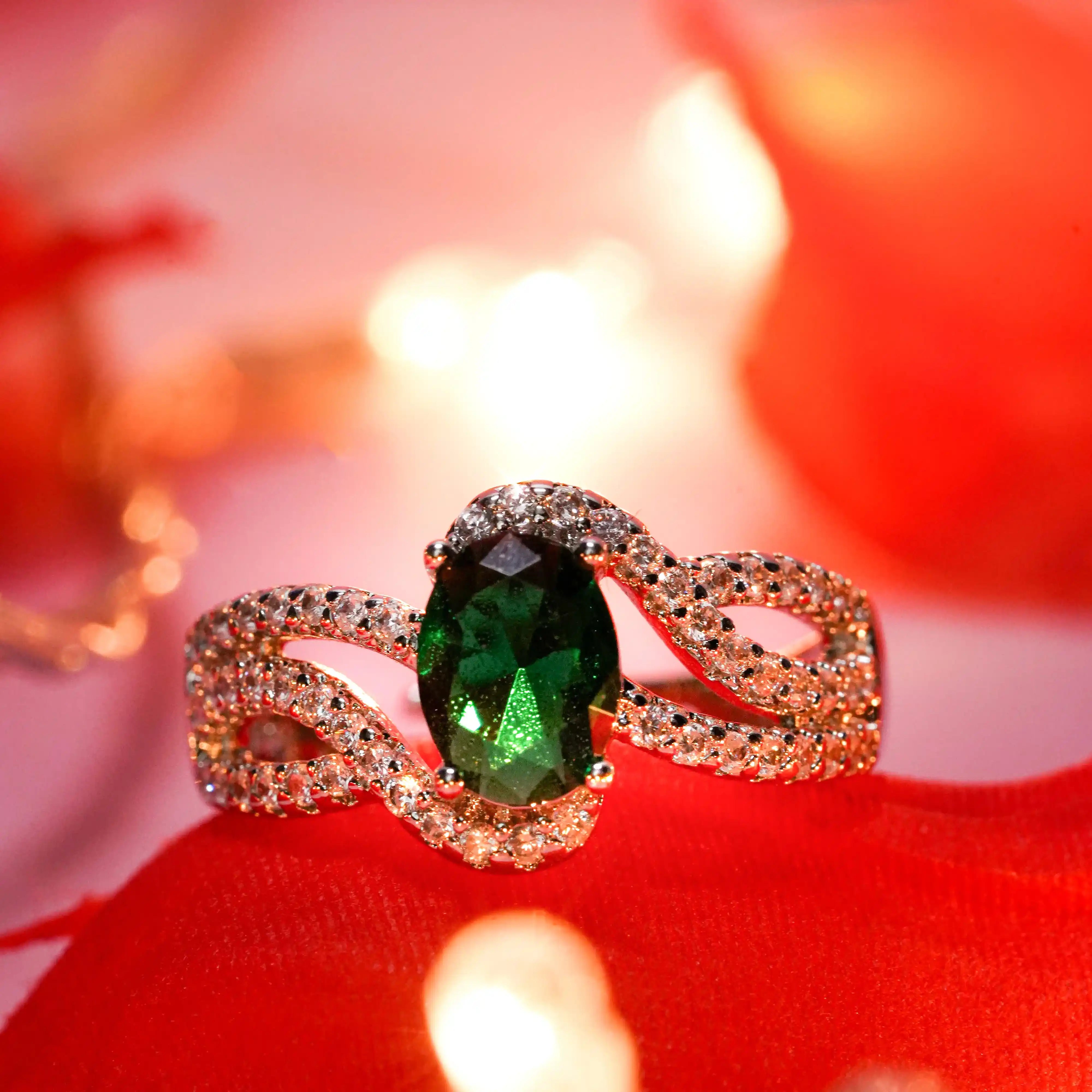 Gold ring with a green gemstone on a red fabric background